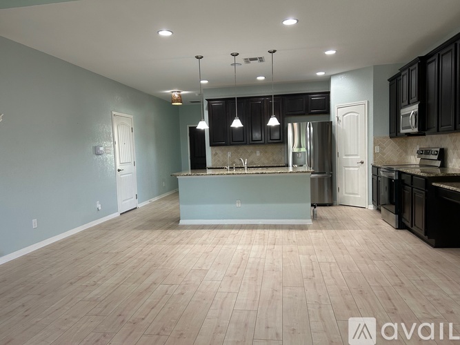 A kitchen with a center island and black cabinets.