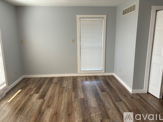 A room with wooden flooring and a window with blinds.