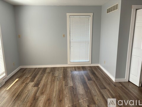 A room with wooden flooring and a window with blinds.