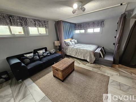 A bedroom with a bed, a sofa, and a rug.