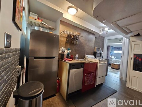 A kitchen with a stainless steel refrigerator and a black trash can.