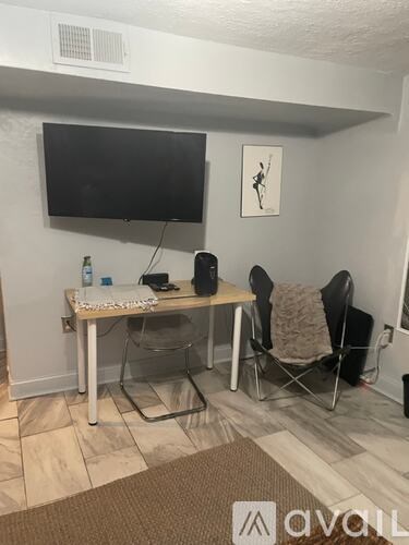A room with a table, chairs, and a television mounted on the wall.