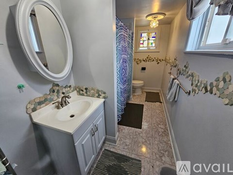 A bathroom with a sink, mirror, and shower.