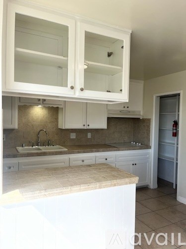 A kitchen with white cabinets and a marble countertop.