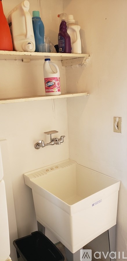 A white sink with a black trash can underneath it.