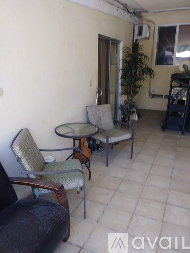 A living room with a glass table and two chairs.