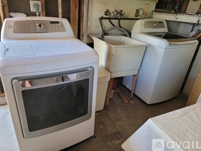 A white oven is in the foreground of a cluttered room.