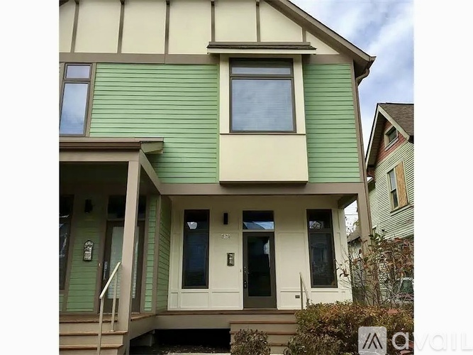 A two-story house with a green siding and a white trim.
