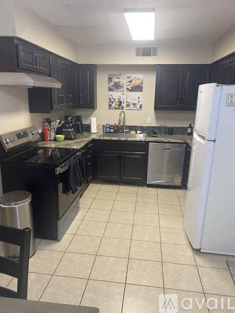 A kitchen with black cabinets and a white refrigerator.