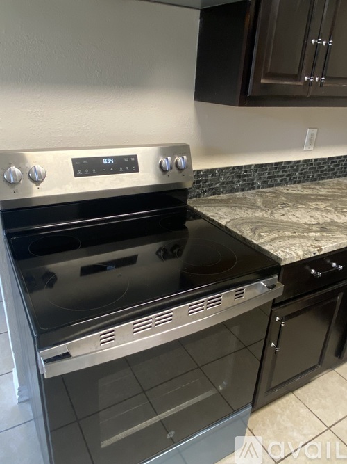 A kitchen with black cabinets and a stainless steel oven.