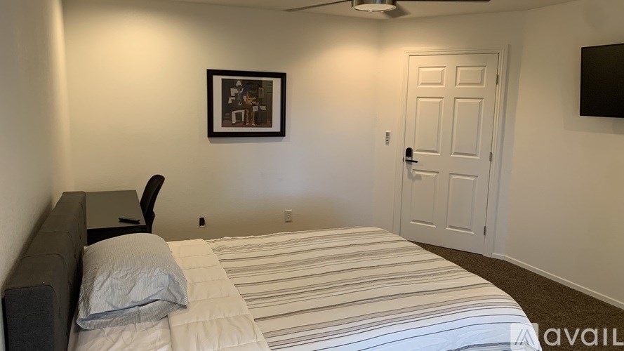 A bedroom with a bed, a chair, and a picture on the wall.