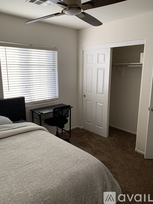 A bedroom with a bed, desk, and chair.