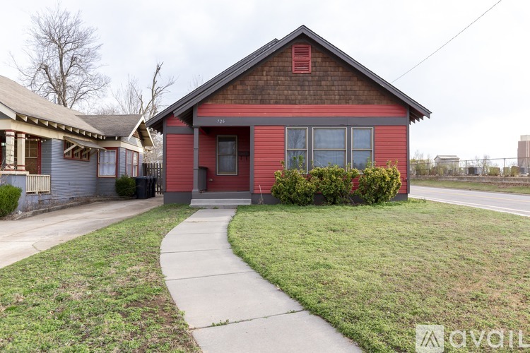 A red house with a brown roof and a grey garage door.