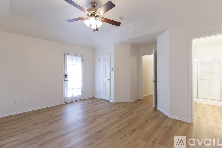 A spacious room with a ceiling fan and wooden flooring.