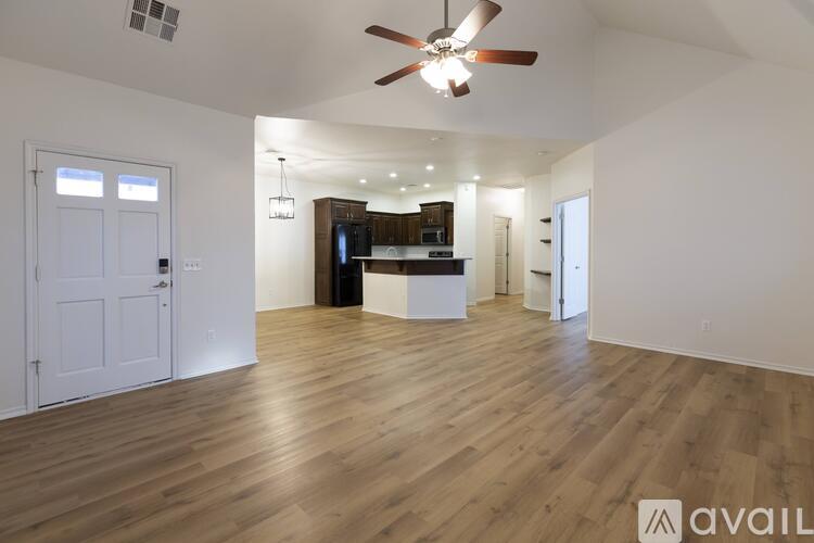 A spacious living room with a ceiling fan and hardwood floors.