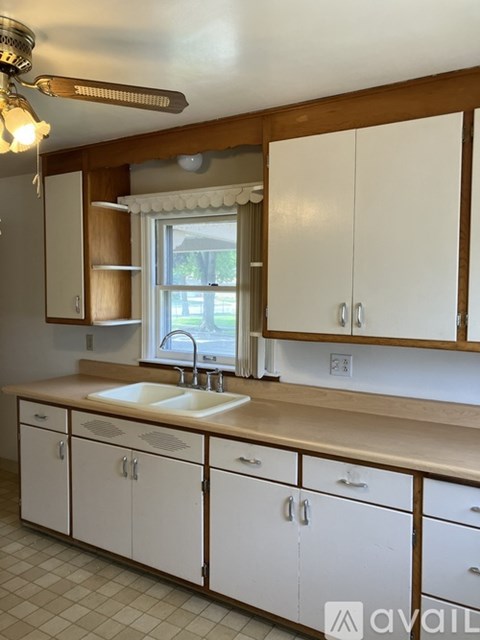A kitchen with white cabinets and a window.