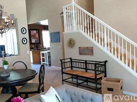 A living room with a couch, a dining table, and a staircase.