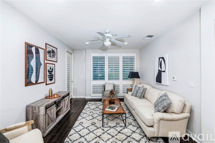 A living room with a white couch, a wooden cabinet, a coffee table, and a ceiling fan.