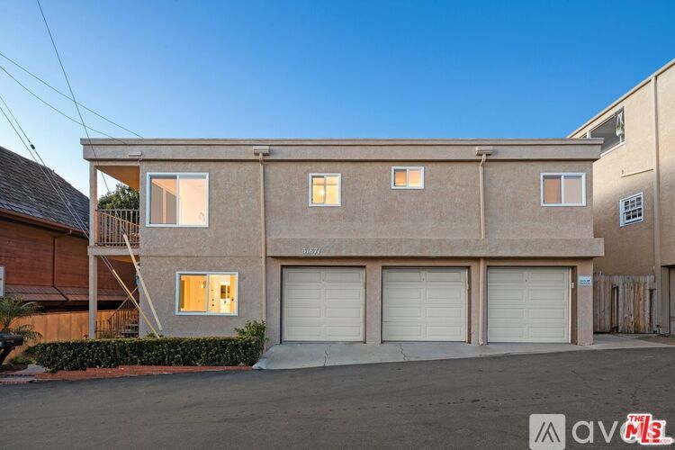 A two-story building with a garage on the ground floor and a balcony on the upper floor.