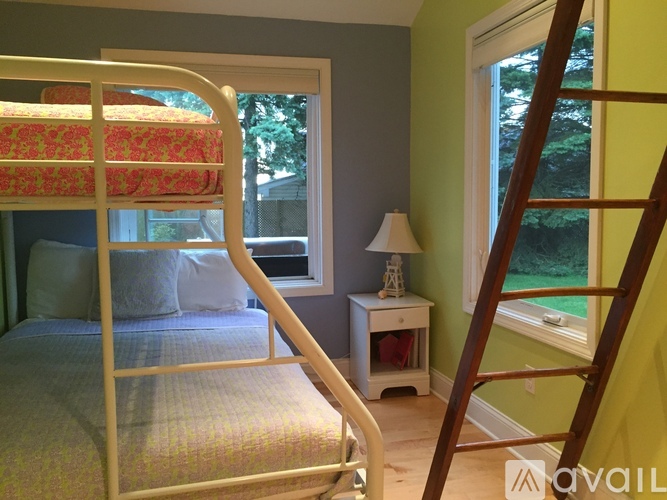 A bedroom with a white metal bed and a small table with a lamp on it.