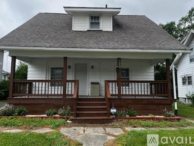 A white house with a brown porch is for sale.