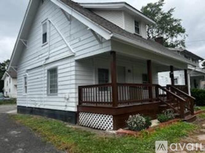 A white house with a brown porch is for sale.