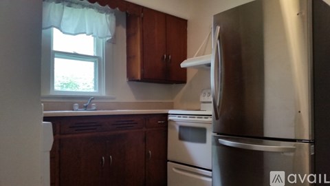 A kitchen with wooden cabinets and a stainless steel refrigerator.