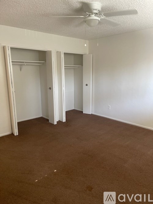 A room with a carpeted floor and a ceiling fan.