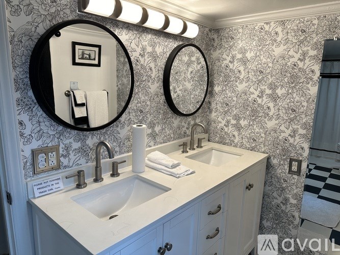 A bathroom with a sink, mirror, and lighting fixture.