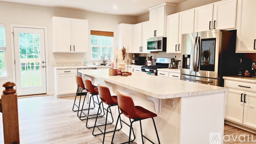 A kitchen with white cabinets and a white island with four chairs.