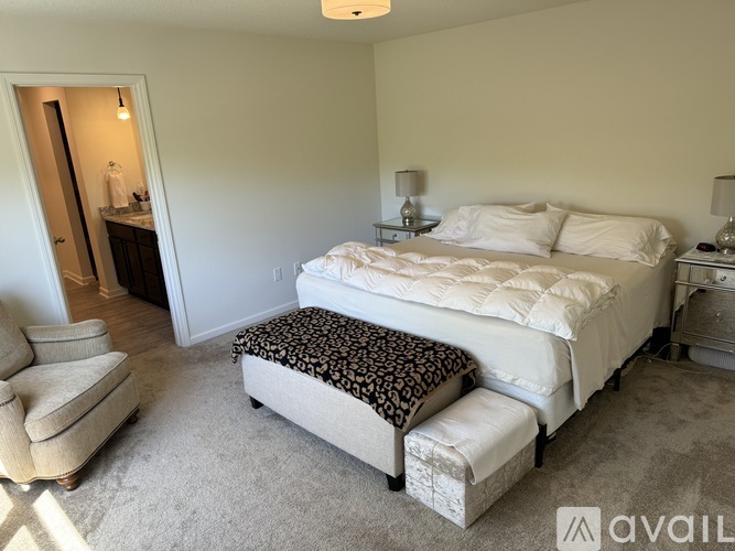 A bedroom with a large bed and a bench in front of it.