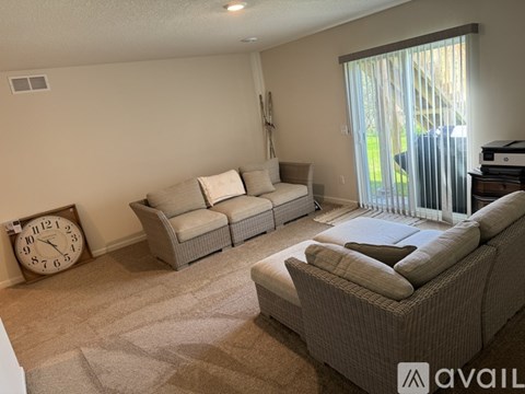 A living room with a sofa set and a clock on the wall.