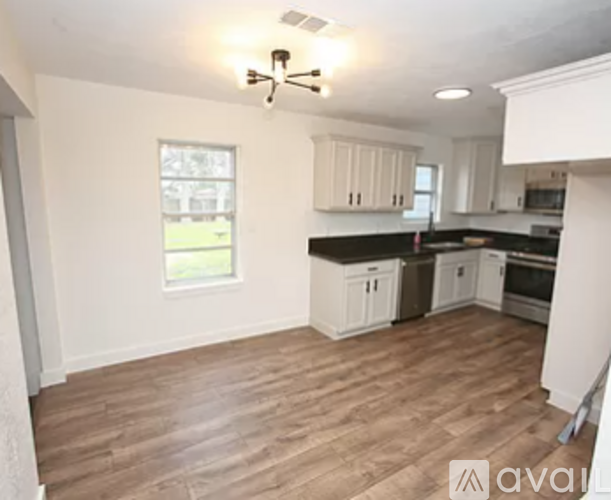 A kitchen with white cabinets and wooden floors.