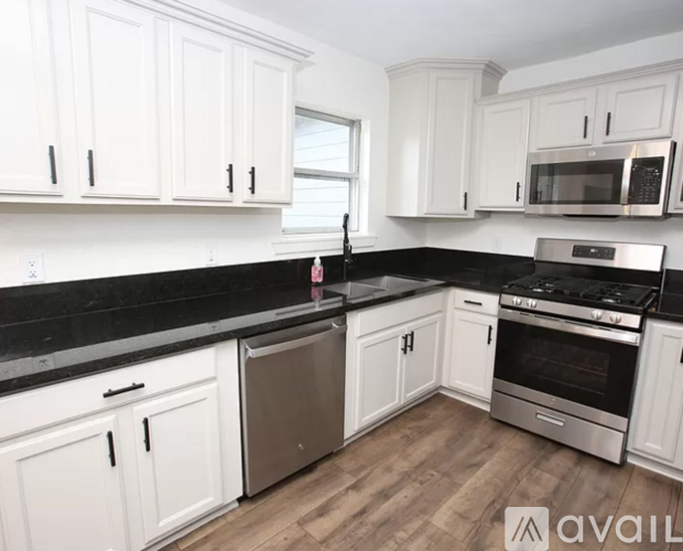 A kitchen with white cabinets and black countertops.