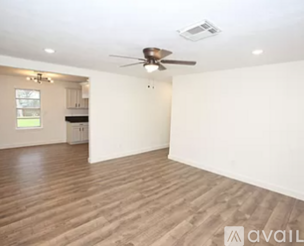 A spacious room with a ceiling fan and wooden flooring.