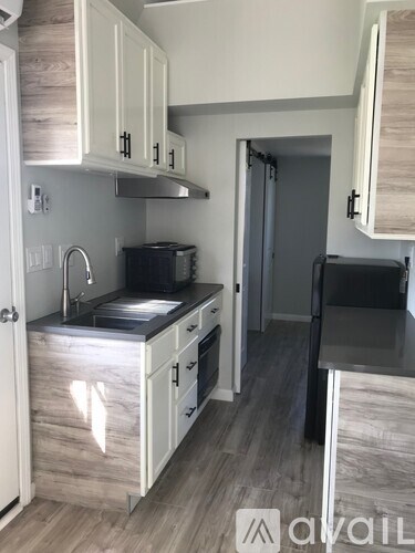 A kitchen with white cabinets and a black countertop.