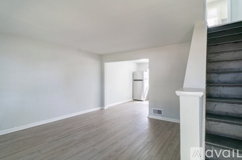 A room with wooden floors and a staircase on the right side.
