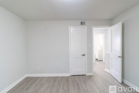A room with a white door and a wooden floor.