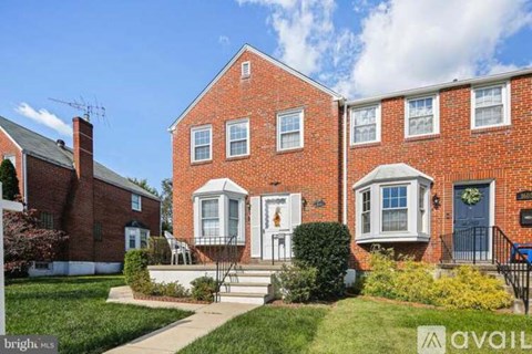 A red brick house with a blue door and a sign that says "available".