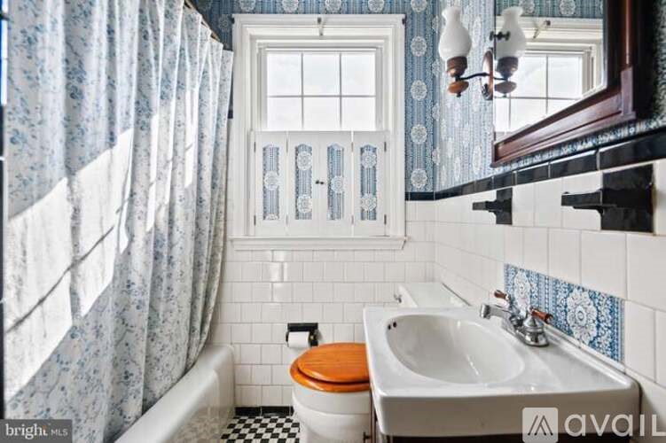 A bathroom with a toilet, sink, and a window.