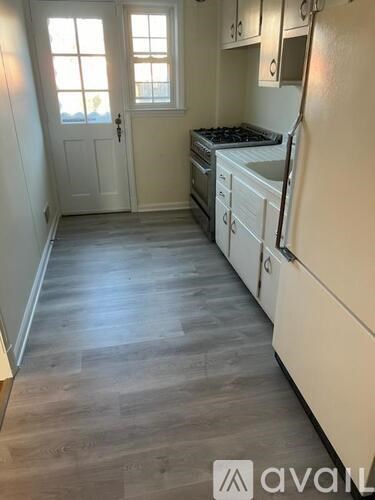 A kitchen with white appliances and wooden floors.