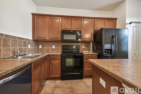 A kitchen with brown cabinets and a black refrigerator.