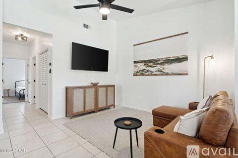 A living room with a brown couch, a black table, and a painting on the wall.