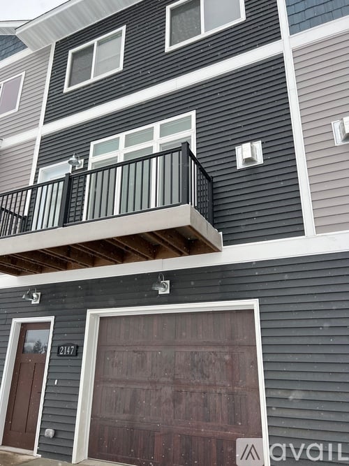 A two-story building with a balcony on the second floor and a garage door on the first floor.