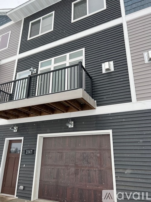 A two-story building with a balcony on the second floor and a garage door on the first floor.