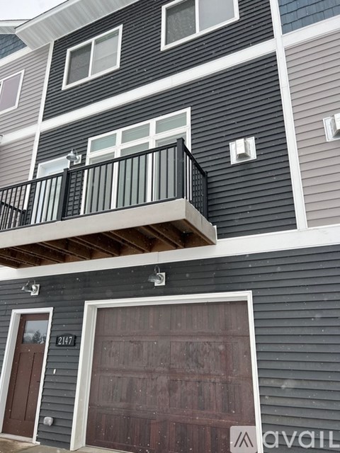 A two-story building with a balcony on the second floor and a garage door on the first floor.