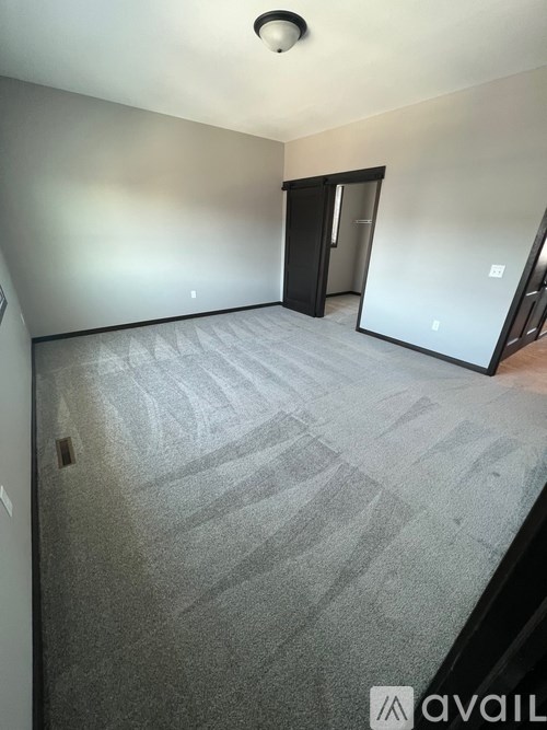 A room with a carpeted floor and a door on the left side.