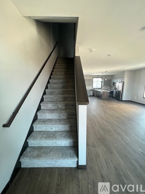 A staircase with a carpeted runner and wooden steps leads to a kitchen area.