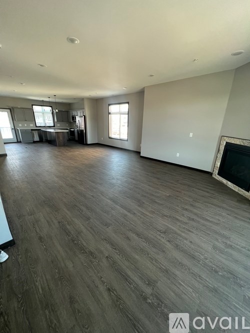 A spacious living room with wooden flooring and a fireplace.