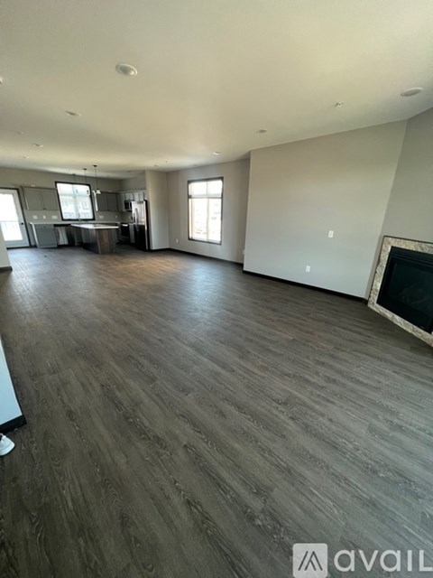 A spacious living room with wooden flooring and a fireplace.